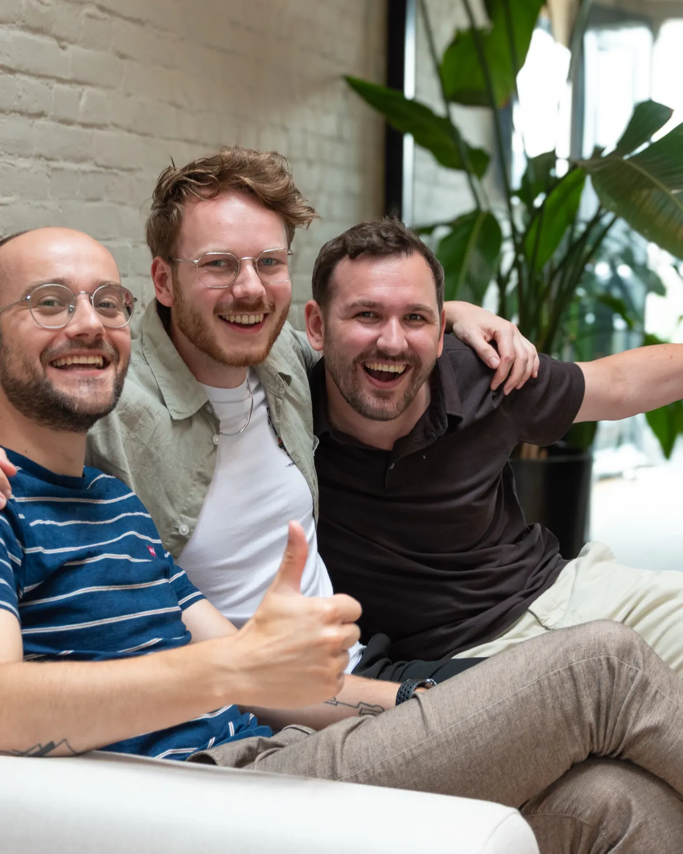 Jasper, Elwin and Bart laughing together on a sofa in the studio